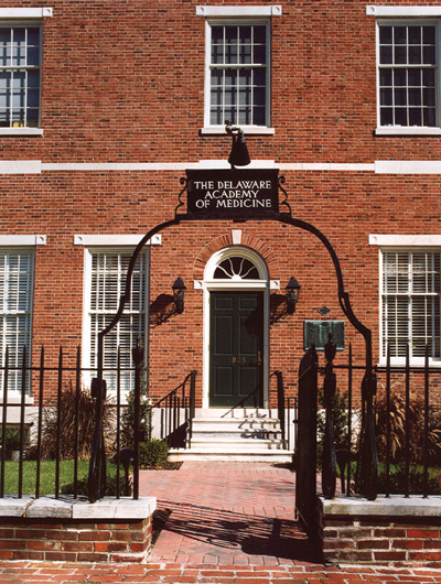 Brick building with an iron gate and a sign that says The Delaware Academy of Medicine